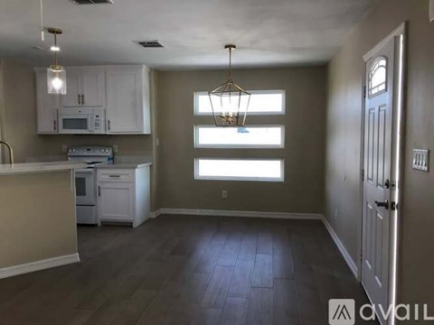 A kitchen with white cabinets and a wooden floor.