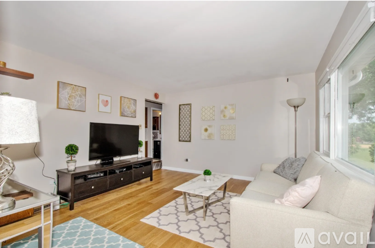 A living room with a white couch, a coffee table, a television, and a lamp.