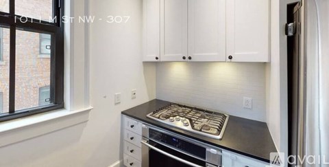 A kitchen with white cabinets and a black countertop.