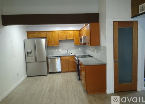 A kitchen with wooden cabinets and a stainless steel refrigerator.