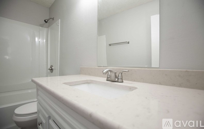 A bathroom with a sink, toilet and mirror.