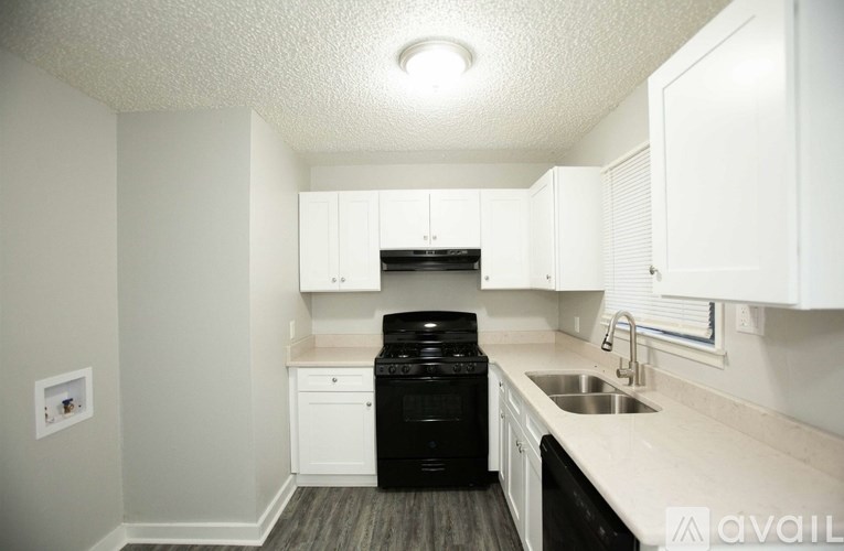 A kitchen with white cabinets and a black dishwasher.