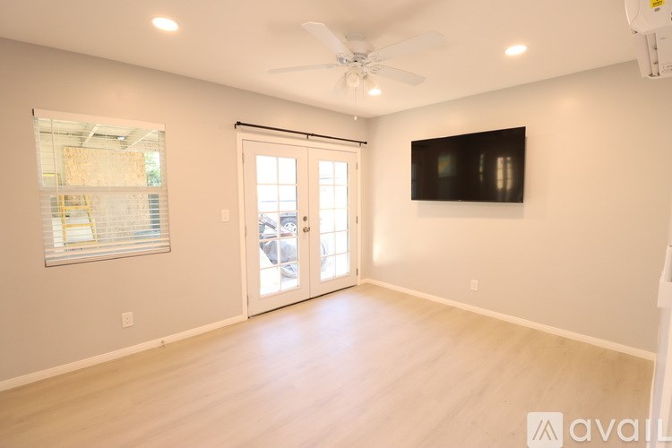 A spacious room with a ceiling fan and a flat-screen TV mounted on the wall.