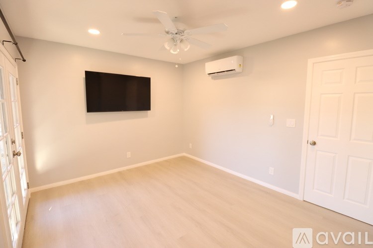 A room with a flat screen TV mounted on the wall and a ceiling fan.