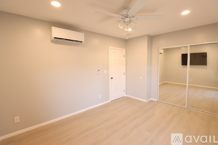 A room with a ceiling fan and sliding glass doors.