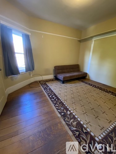 A living room with a brown couch and a patterned rug.