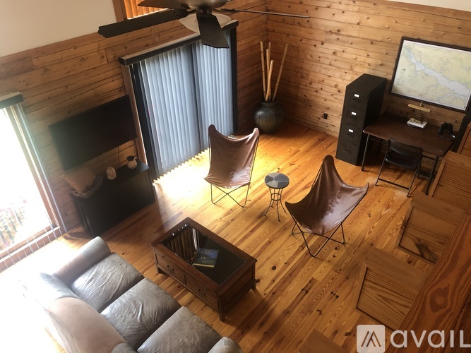 A living room with a brown leather chair and a wooden floor.