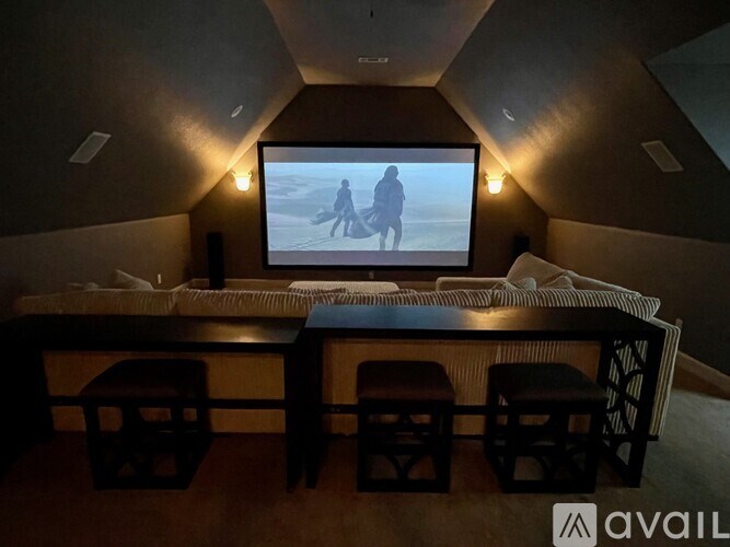 A room with a large screen and a bed with a striped blanket.