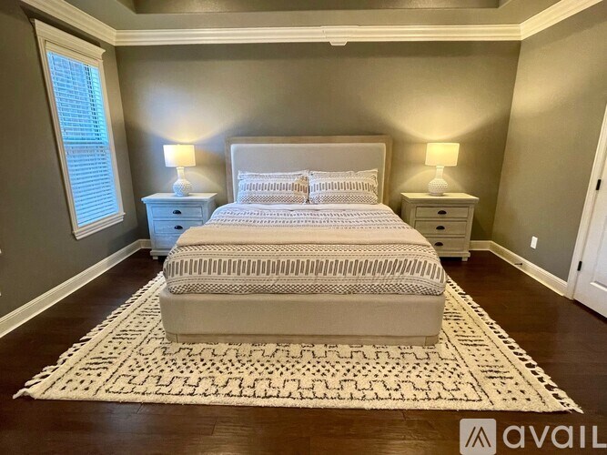 A bedroom with a large bed and two lamps.