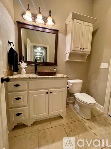 A bathroom with a toilet, sink, and mirror.