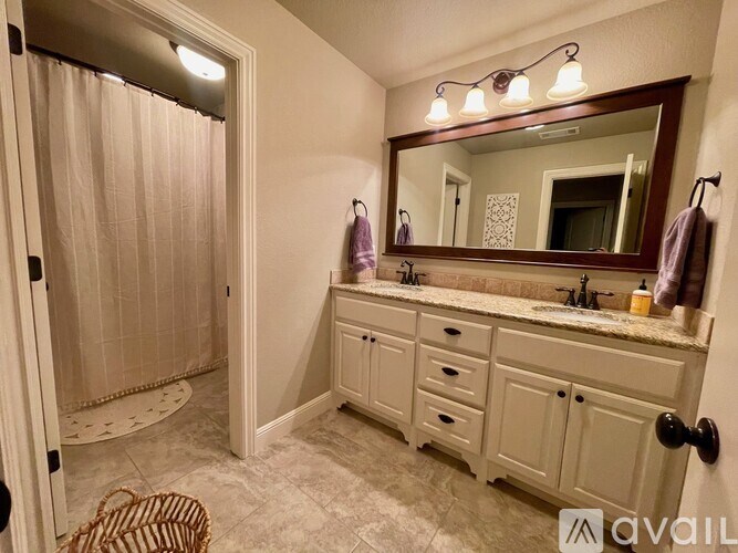 A bathroom with a vanity, mirror, and shower.