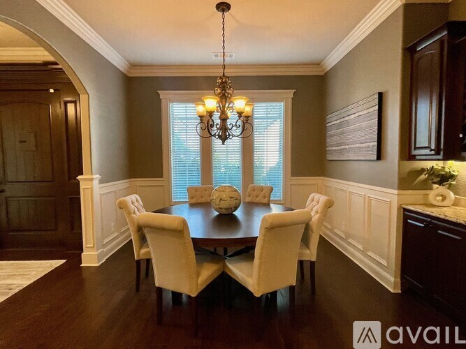A dining room with a chandelier, four chairs, and a table.