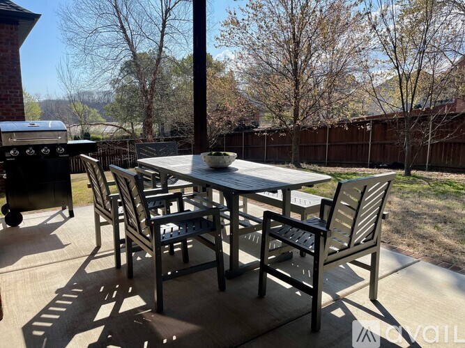 A patio with a table and chairs and a grill.