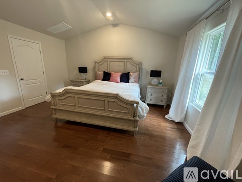 A bedroom with a large bed and wooden floors.