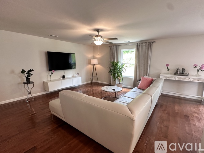 A living room with a white couch and a television mounted on the wall.