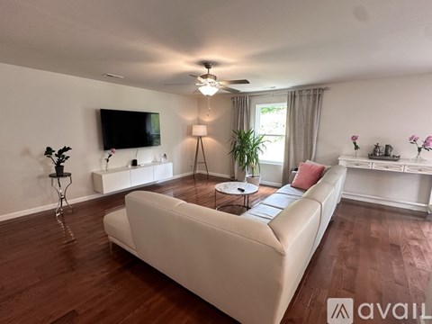 A living room with a white couch and a television mounted on the wall.