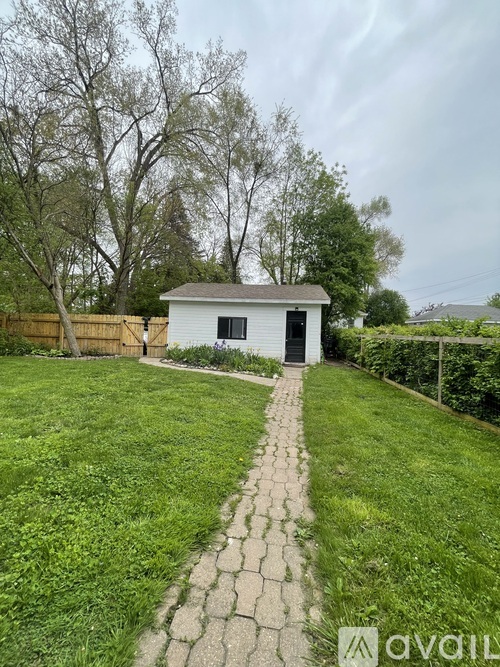 A small white shed sits in a grassy backyard.