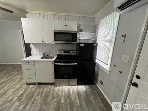 A kitchen with white cabinets and black appliances.