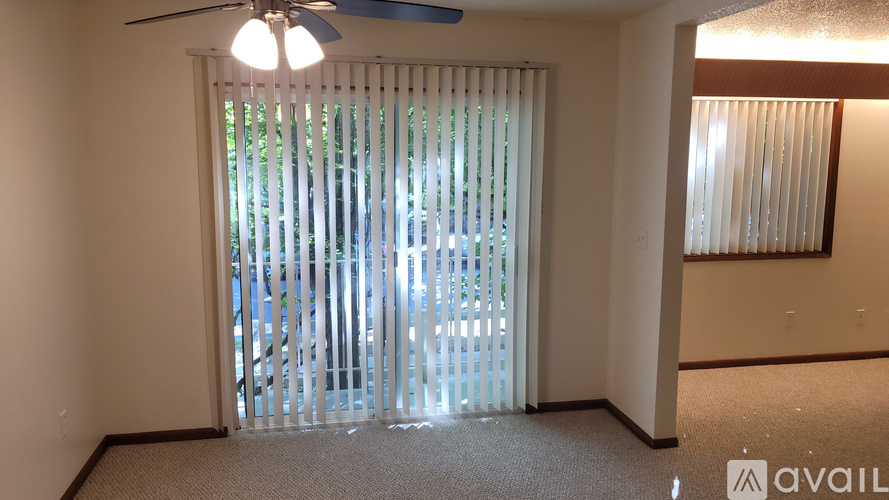 A room with a fan and a window with blinds.