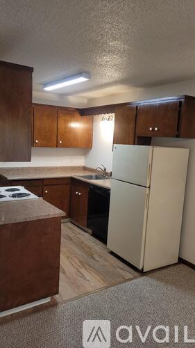 A kitchen with a white refrigerator and wooden cabinets.