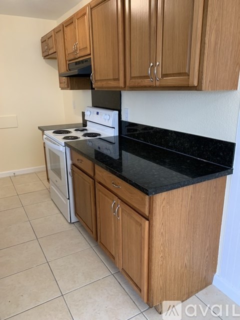 A kitchen with wooden cabinets and a black countertop.