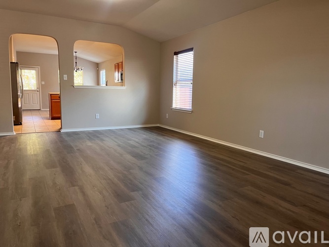 A spacious room with wooden flooring and a large window.