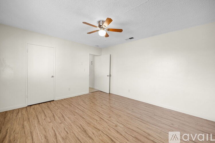 A room with a ceiling fan and wooden flooring.