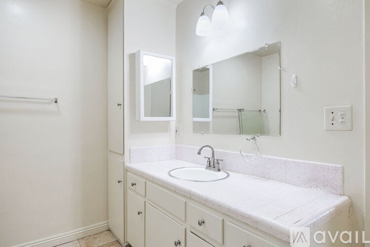 A bathroom with a sink, mirror, and cabinet.