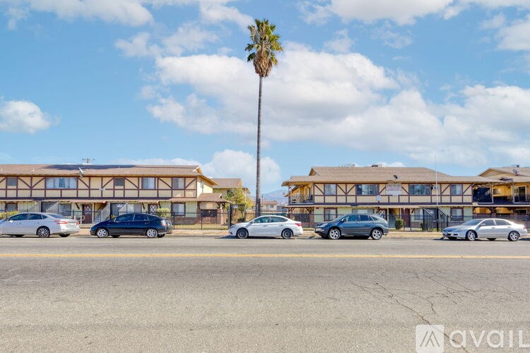 A parking lot with cars and a building with a palm tree in front.