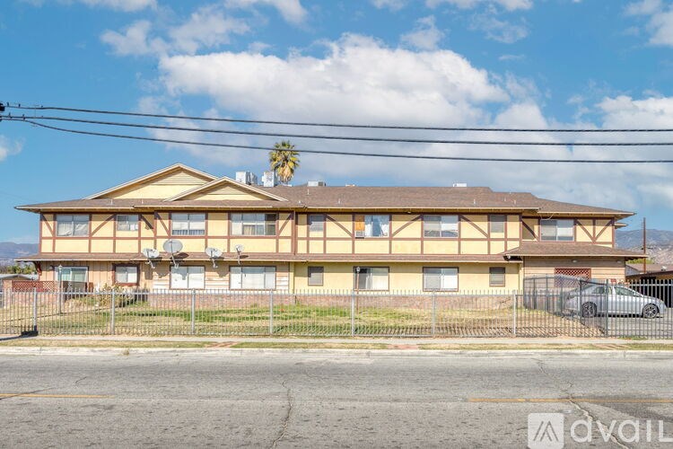 A large two-story building with a yellow and brown exterior and a palm tree on the roof.