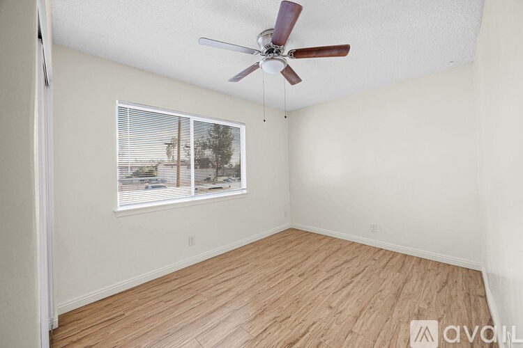 A room with a ceiling fan and a window with blinds.