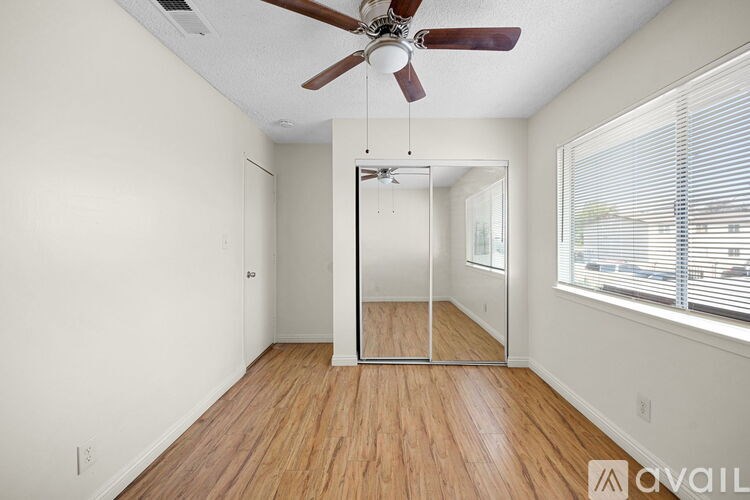 A room with a ceiling fan and a sliding glass door leading to a balcony.