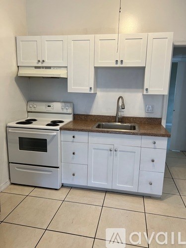 A kitchen with white cabinets and a stove top oven.