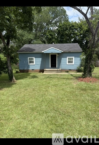A small blue house with a porch and a tree in front.