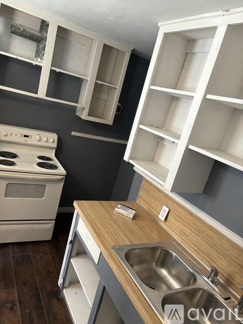 A kitchen with a stove, sink, and shelves.