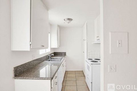 A kitchen with white cabinets and a granite countertop.