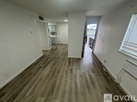 A room with wooden flooring and a window on the right side.