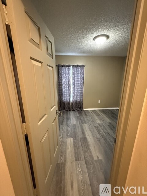 A hallway with a white door and a curtain hanging in the background.