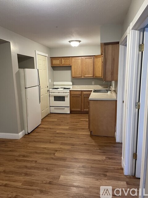 A kitchen with wooden floors and white appliances.