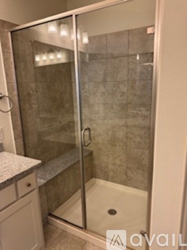 A glass shower stall with a white bench seat.