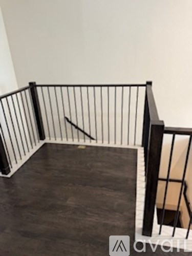 A balcony with a black railing and a wooden floor.