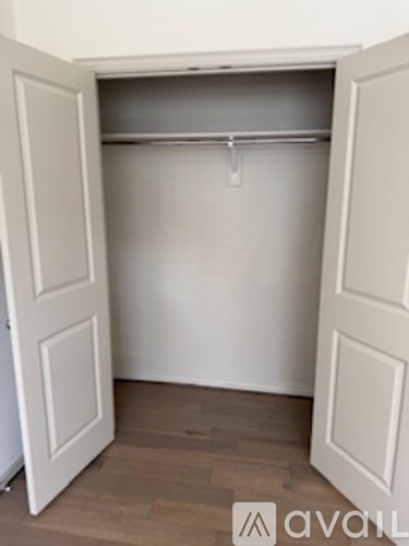 A white closet with a hanger bar and wooden floors.