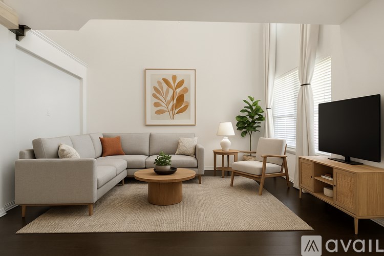 A living room with a grey sofa, a wooden coffee table, a TV, and a plant.