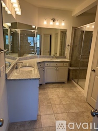 A bathroom with a sink, mirror, and shower.