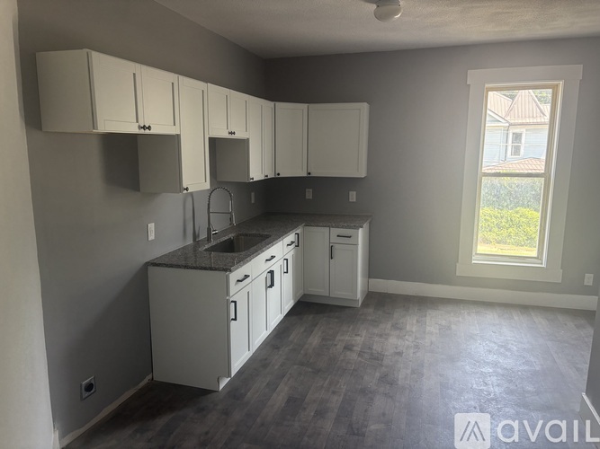 A kitchen with white cabinets and a window.