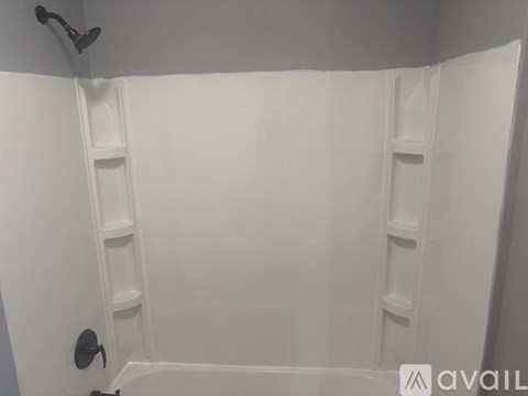 A white bathroom with a shower and a black handle.