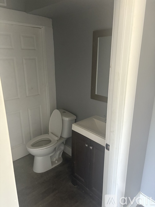 A white toilet sits in a small bathroom next to a cabinet.