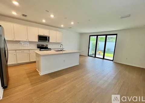 A kitchen with white cabinets and a wooden floor.