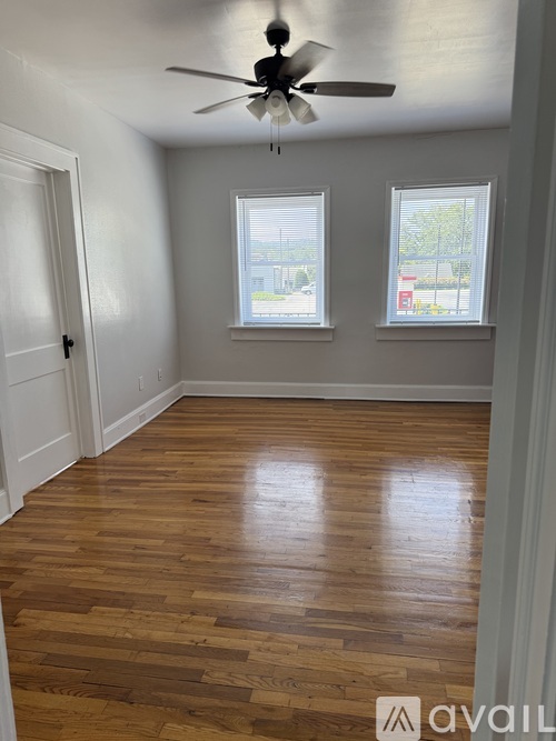 A room with a ceiling fan and two windows.