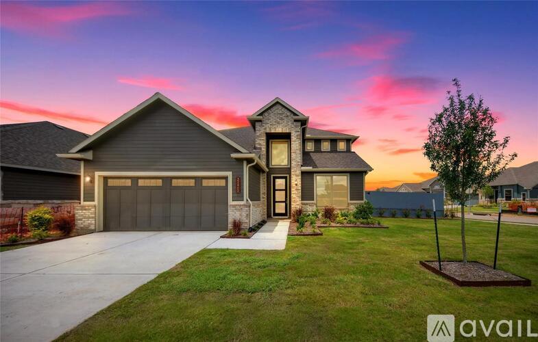 A house with a garage and a tree in front of it.